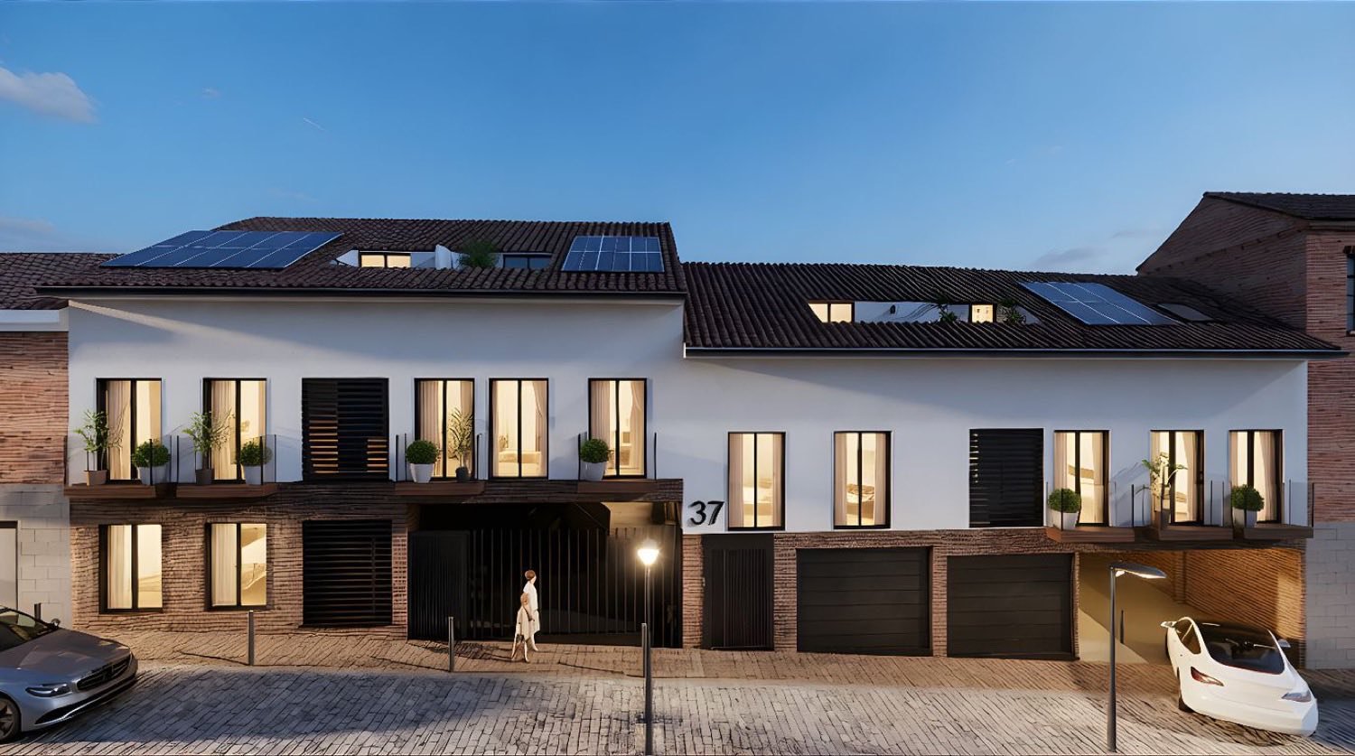 Render de la fachada del Edificio Huertas con los portales y accesos al garaje iluminados al anochecer.